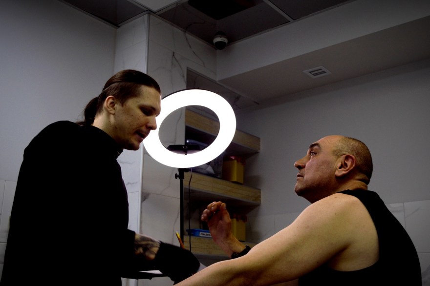 A military vet looks at a tatto artist in a studio in Kyiv.